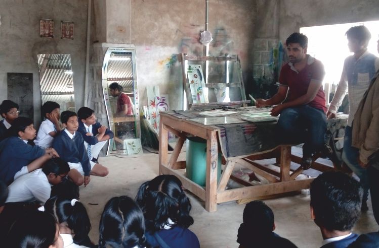 Students seated around a craftsman demonstrating glass art at his workshop